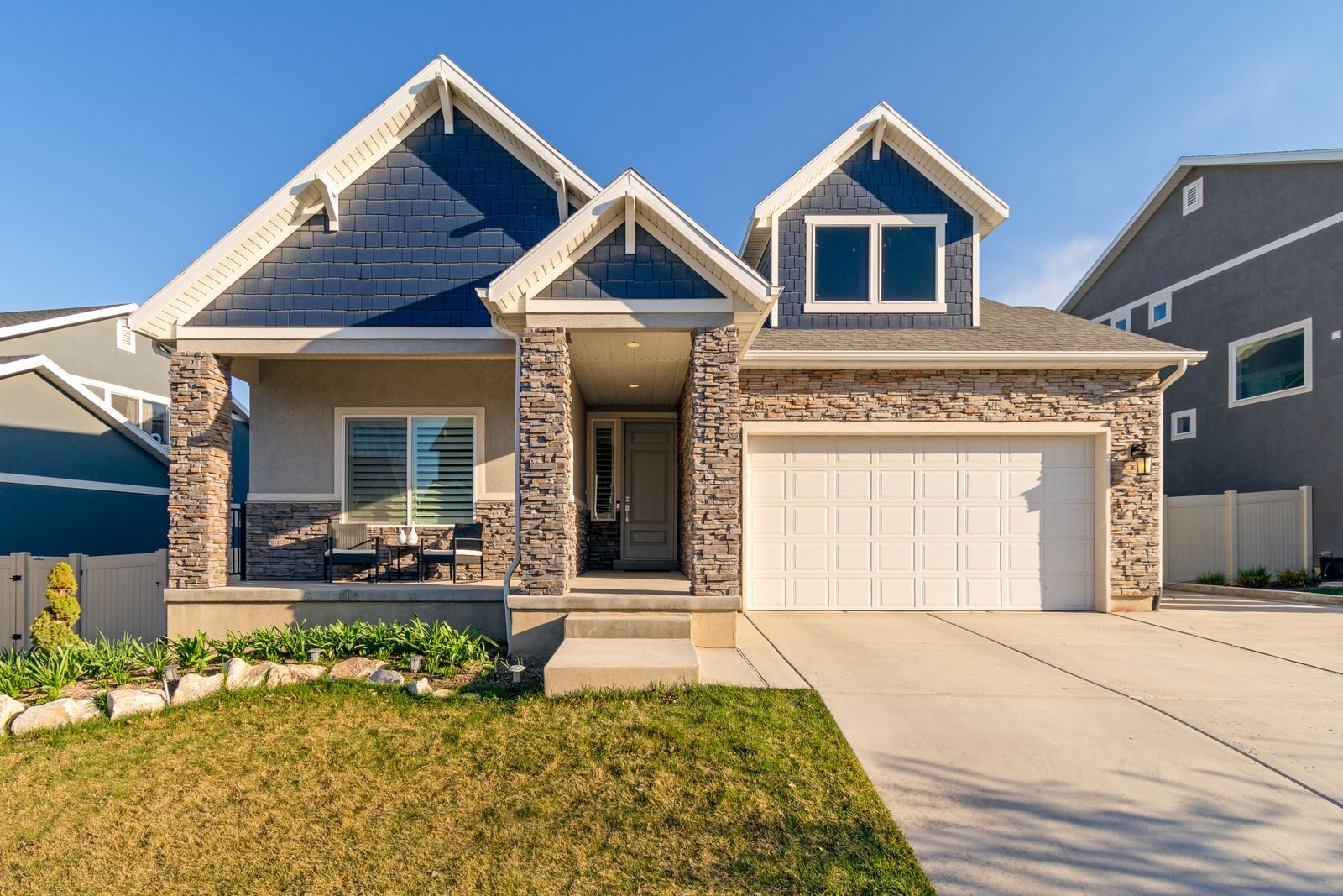 Detached suburban house with a front porch and landscaped lawn.