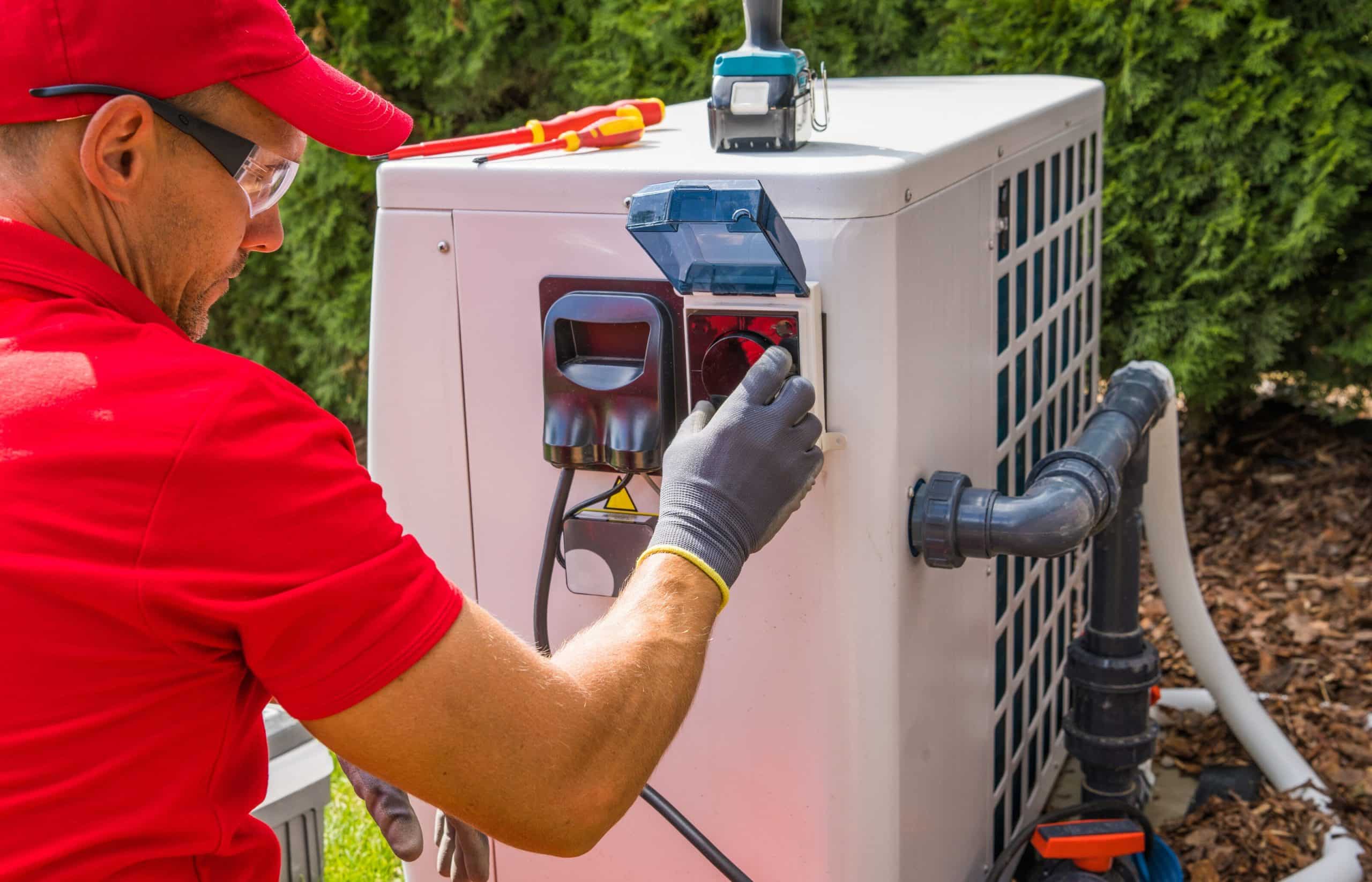 A technician inspecting an outdoor heating and cooling condenser beside a clapboard-sided home.